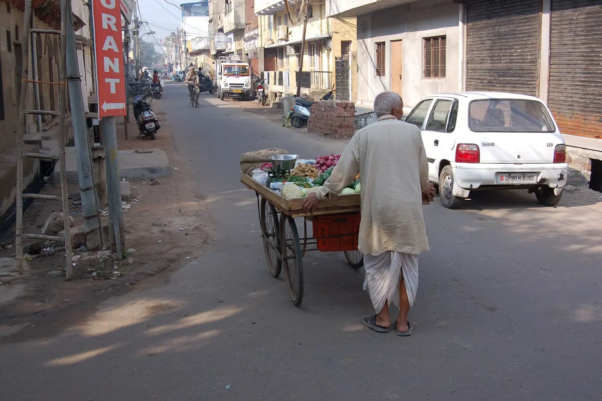 Man pushing a produce cart along a narrow Agra back street