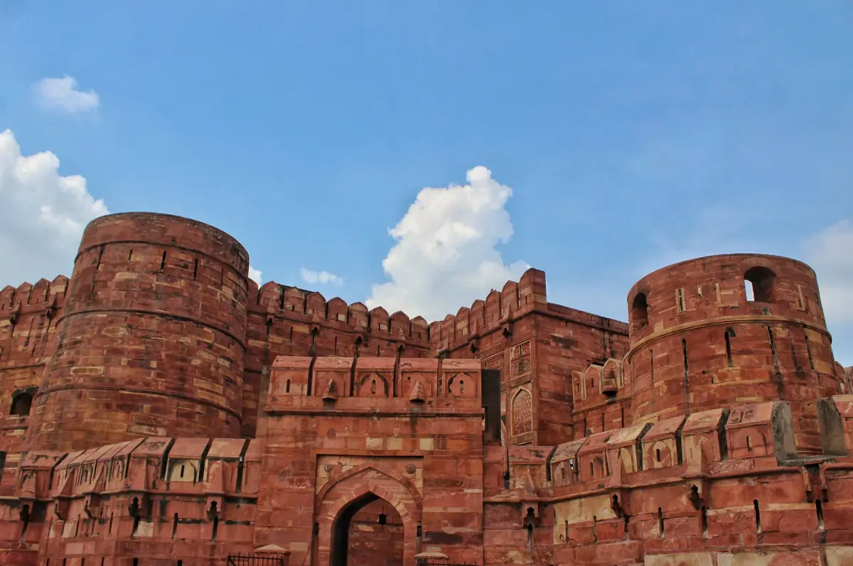 Massive red curtain wall and round bastions of Agra Fort against a blue sky