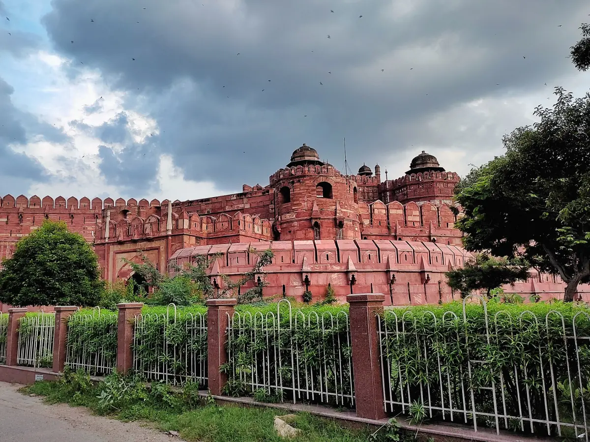 Delhi Gate of Agra Fort rising above a hedge and lawn in the park